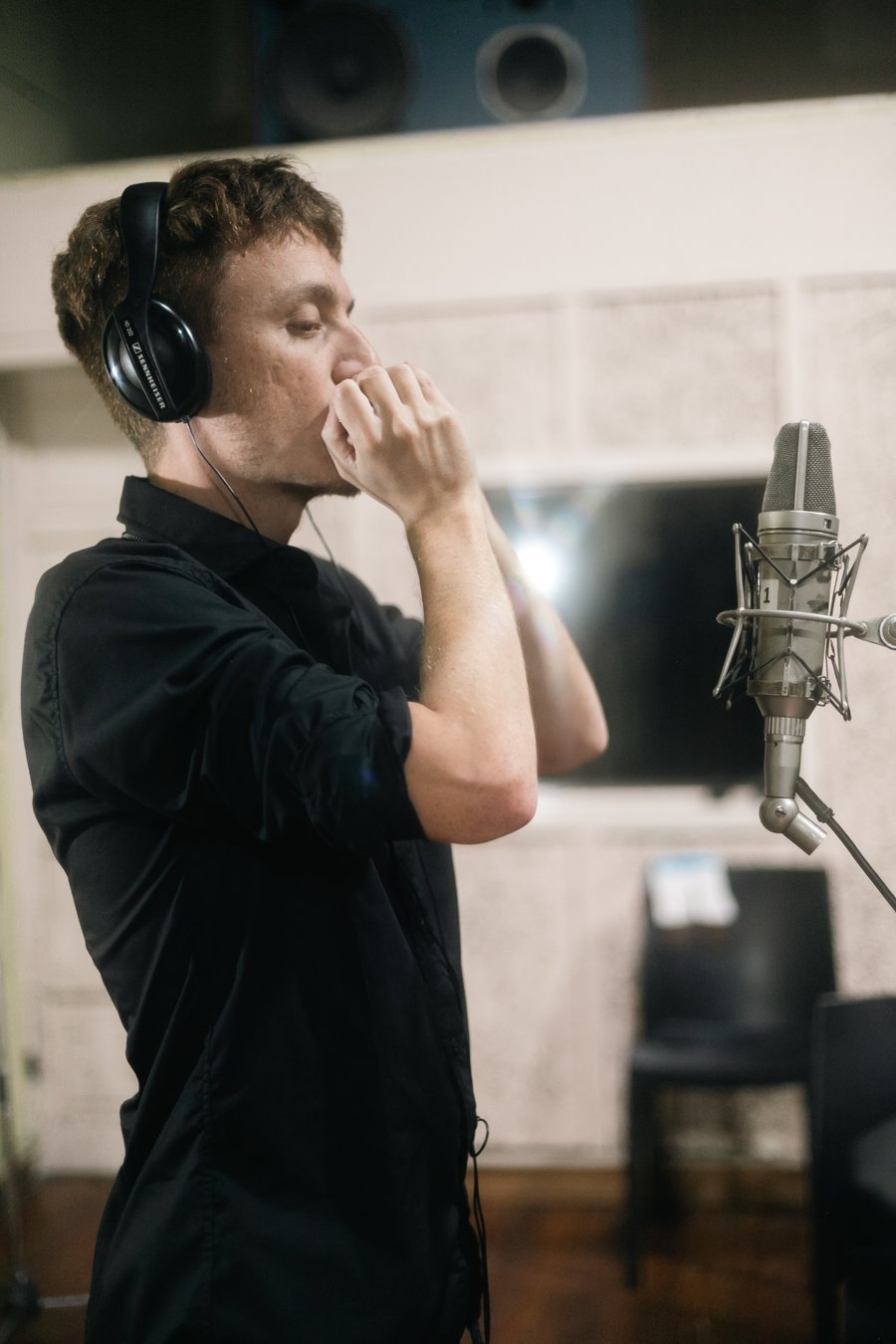 Federico Linari playing harmonica into a studio microphone